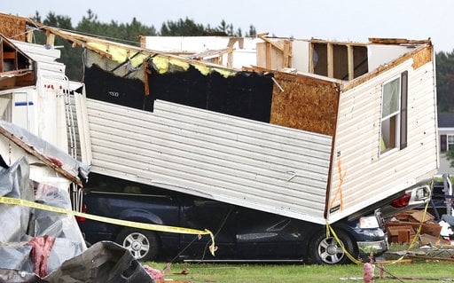 Part of a building sits on a vehicle after a tornado ripped through Prairie Lake Estates trailer home park