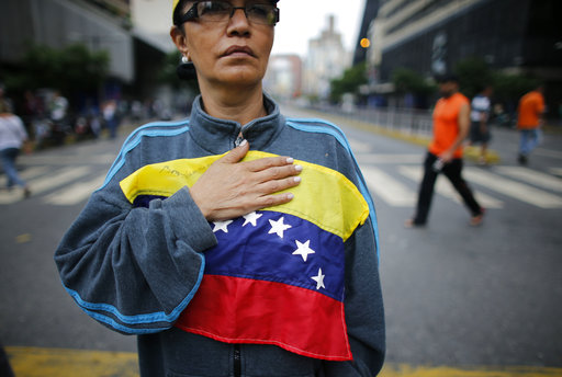 A woman holds a Venezuelan flag on her chest as she joins a roadblock in Caracas