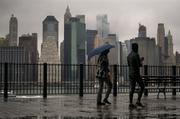 Passersby walk along the Promenade in the Brooklyn Heights neighborhood as rain and clouds loom over lower Manhattan on the fifth anniversary of Superstorm Sandy Sunday