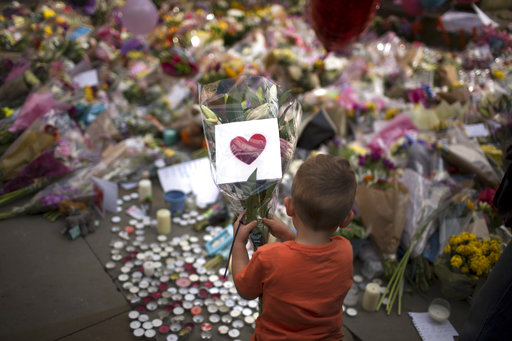 A child places flowers in a square in central Manchester