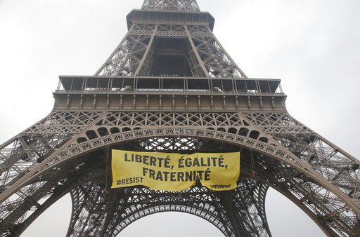 Greenpeace activists display a banner at the Eiffel tower reads