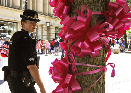 Police patrol past a pink ribbon tribute in central Manchester