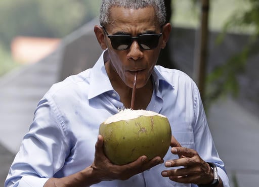 U.S. President Barack Obama drinks from a fresh coconut along the banks of the Mekong River in the Luang Prabang