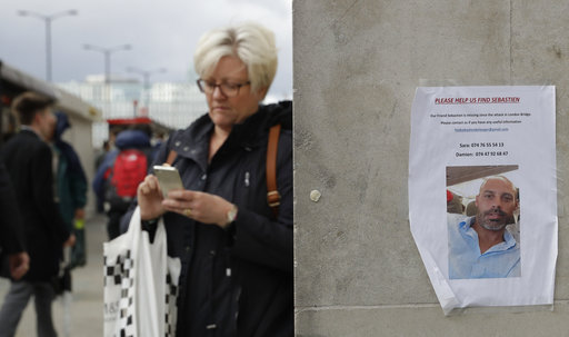 A woman walks by a poster of a missing man in the London Bridge area of London on Tuesday