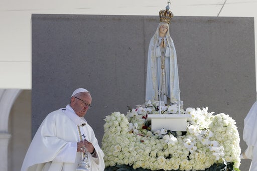 Pope Francis walks past a statue of the Virgin Mary prior to the start of a mass at the Sanctuary of Our Lady of Fatima Saturday