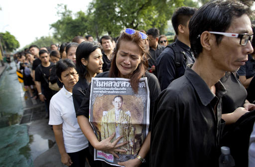 A Thai woman weeps as she holds on to a portrait of Thai King Bhumibol Adulyadej in a line to offer condolences for the king at Grand Palace in Bangkok