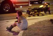 A woman sits on a curb at the scene of a shooting outside of a music festival along the Las Vegas Strip