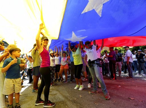 Opposition members wave a Venezuelan flag outside a poll station during a symbolic referendum in Caracas