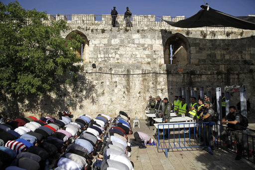 Israeli border police officers stand guard as Muslim men pray outside the Al Aqsa Mosque compound