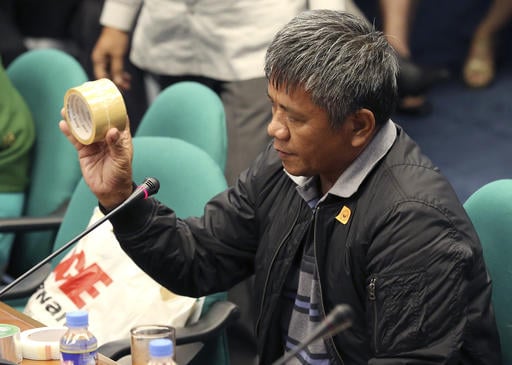 Former Filipino militiaman Edgar Matobato shows the kind of tape they use to wrap up dead bodies as he testifies before the Philippine Senate in Pasay