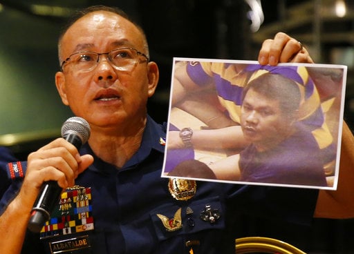Police Gen. Oscar Albayalde holds a copy of an image of a gunman who stormed the Resorts World Manila complex whom he identified as Jessie Carlos during a news conference Sunday