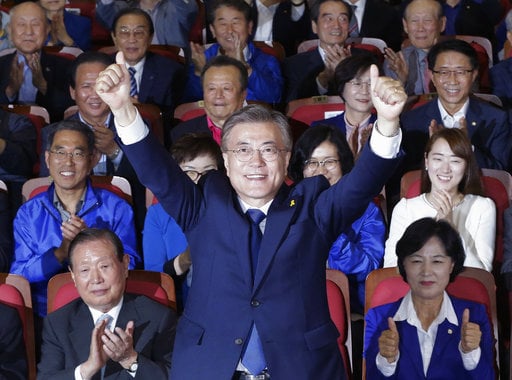 South Korea's presidential candidate Moon Jae-in of the Democratic Party raises his hands as his party leaders and members watch on television local media's results of exit polls for the presidential election in Seoul