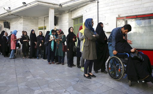 Iranian voters queue at a polling station for the presidential and municipal council election in Tehran