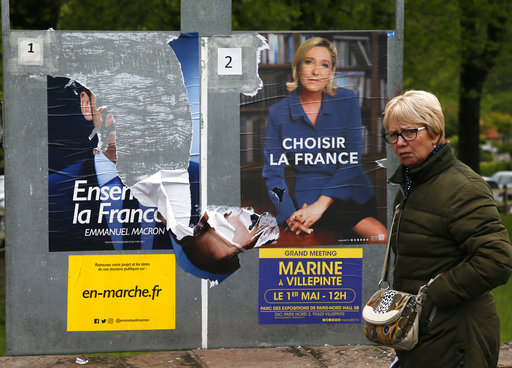 A woman walks past electoral posters of French centrist presidential candidate Emmanuel Macron