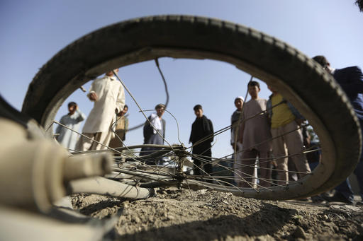 Afghan civilians watch a damaged bicycle after a bomb explosion targeted an army vehicle in Kabul