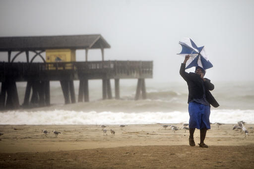 Preston Payne tires to hold his umbrella as he watches the waves near the Tybee pier as Hurricane Matthew makes its way up the East Coast