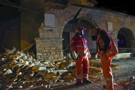 Rescuers stand by rubble in the village of Visso