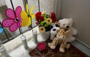 Candles and stuff animals of a makeshift memorial sit outside an apartment Thursday