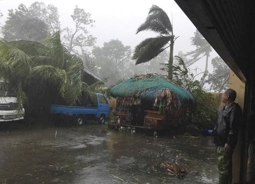 A man takes cover as strong winds and rain topple trees while Typhoon Haima lashes Narvacan