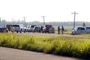 Emergency personnel stand along U.S. Highway 82 after a military transport plane crashed into a field near Itta Bena