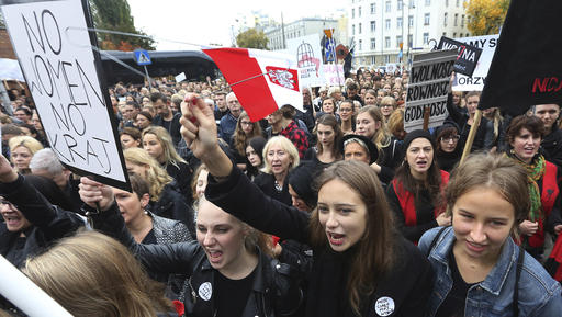 Polish women shout slogans while raising a hanger