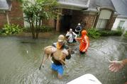 Volunteers evacuate a neighborhood inundated by floodwaters from Tropical Storm Harvey on Monday