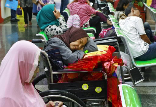 A patient takes a nap on her wheelchair as she waits with others at the registration desk at Dharmais Cancer Hospital in Jakarta