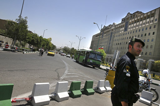 A police officer stands guard as vehicles drive in front of Iran's parliament building in Tehran