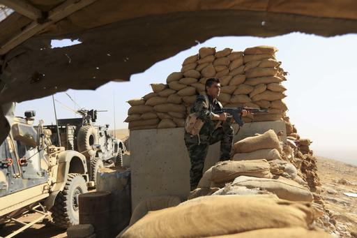An Iraqi Kurdish Peshmerga fighter stands guard outside Bartella