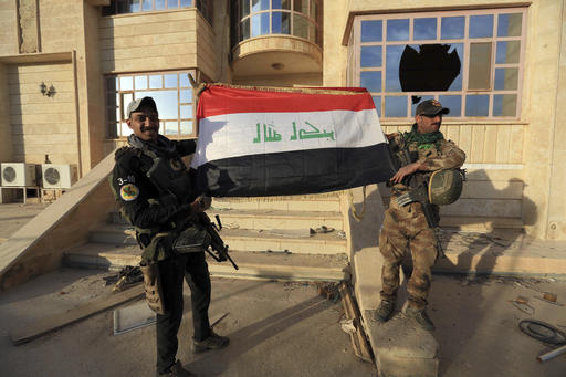 Iraq's elite counterterrorism force soldiers raise an Iraqi flag in front of the main church in Bartella