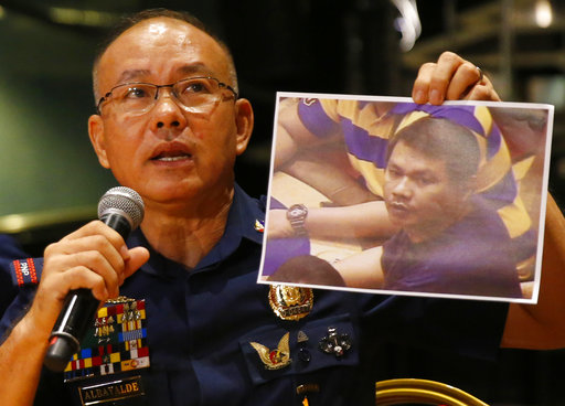 Police Gen. Oscar Albayalde holds a copy of an image of a gunman who stormed the Resorts World Manila complex whom he identified as Jessie Carlos during a news conference Sunday