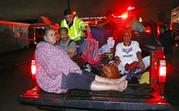 Residents ride in the bed of an emergency vehicle carrying them to safety following flooding to their homes late Monday night