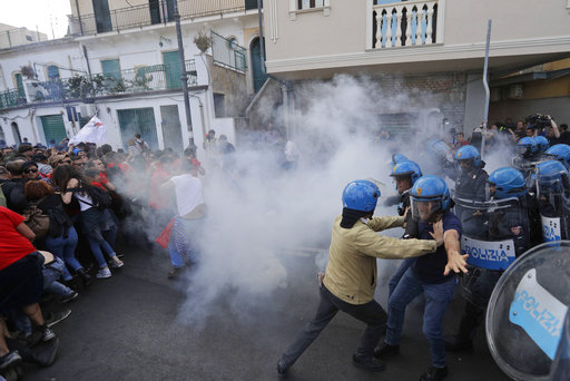 A police officer holds back other policemen as some demonstrators do the same with their side after a contact during an anti-G7 rally near the venue of the G7 summit in the Sicilian town of Taormina