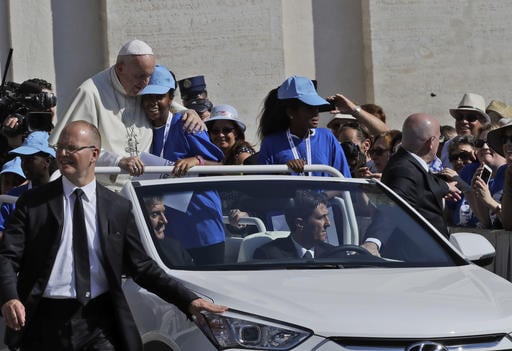 Pope Francis hugs a girl on his pope mobile upon his arrival in St. Peter's Square at the Vatican for a jubilee audience for workers and volunteers of mercy