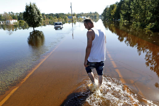 Elmer McDonald makes his way along the flooded street to his home as he returns to his mobile home for the first time to inspect damage caused by floodwaters associated with Hurricane Matthew on Thursday