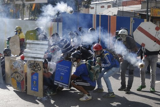 Anti-government protesters shield themselves from tear gas as security forces try to disperse them