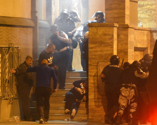 People react as a stun grenade explodes by a parliament entrance