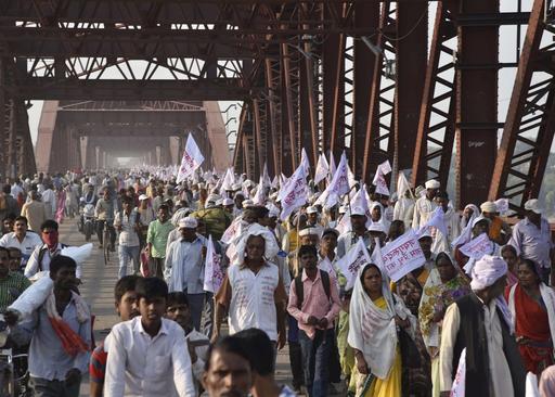 Hindu pilgrims hold religious flags and walk on a crowded bridge after a stampede on the same bridge on the outskirts of Varanasi