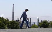The stacks from the Valero Benicia Refinery are seen as a pedestrian walks in a nearby neighborhood