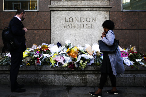 People look at the floral tributes placed at London Bridge to commemorate the victims of Saturday's attack in London