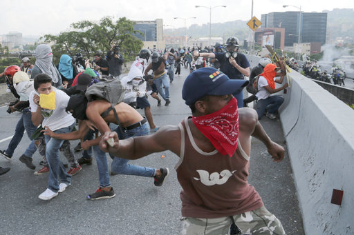 Anti-government protesters throw stones from a highway overpass at a passing police patrol in Caracas