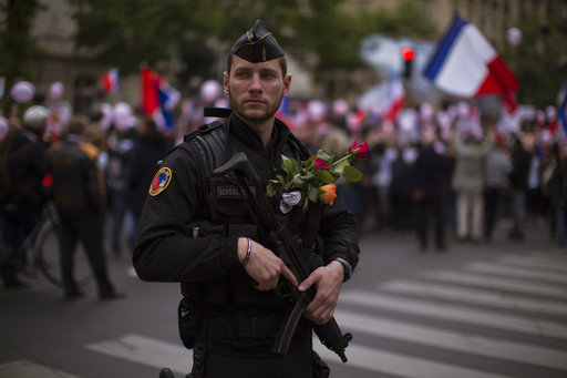 A French riot police officer carries flowers given to him by a protestor who demonstrated with others in what was described as a march of support for all French security forces