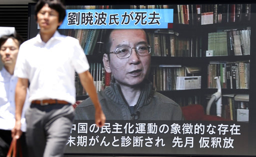 People walk by an image of Chinese Nobel Peace Prize laureate Liu Xiaobo shown on a large screen as a TV news reports Liu's death in Tokyo