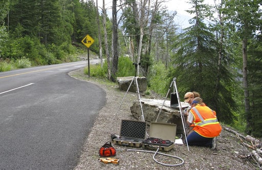 In this photo provided by the National Park Service a National Park Service staffer sets up an acoustic recording station on Going-to-the-Sun Road to capture the impact of traffic on acoustic conditions in Glacier National Park