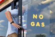 A customer walks into an Exxon filling station and convenience store location where a sign on the door reads