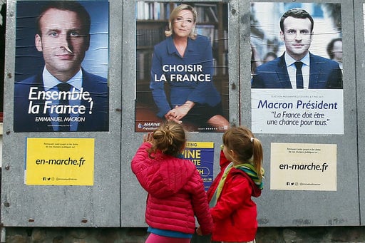 Children walk past election campaign posters for French centrist presidential candidate Emmanuel Macron and far-right candidate Marine Le Pen