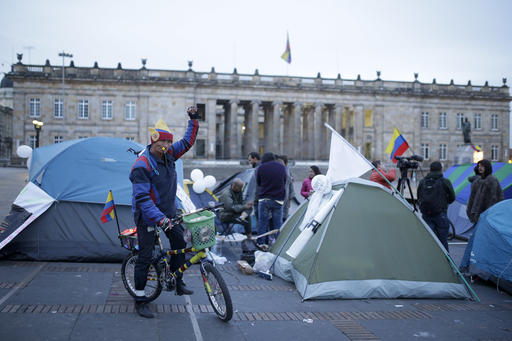 A cyclist raises his arm next to students camping to ask for peace at the main square in Bogota