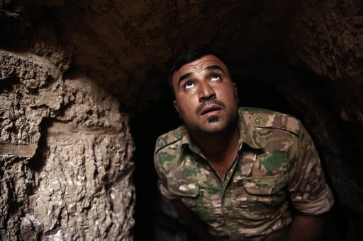 A peshmerga fighter looks out of the entrance of an underground tunnel built by Islamic State fighters