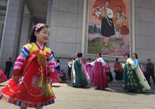 A young girl watches as North Korean men and women take part in a mass dance on Tuesday
