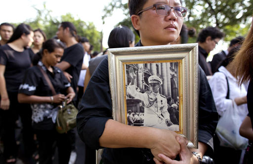 A Thai woman holds on to a portrait of Thai King Bhumibol Adulyadej in a line to offer condolences for the king at Grand Palace in Bangkok